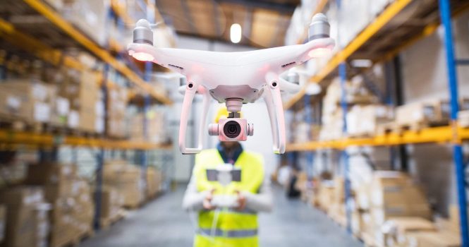 Man or a worker with drone standing in a warehouse.